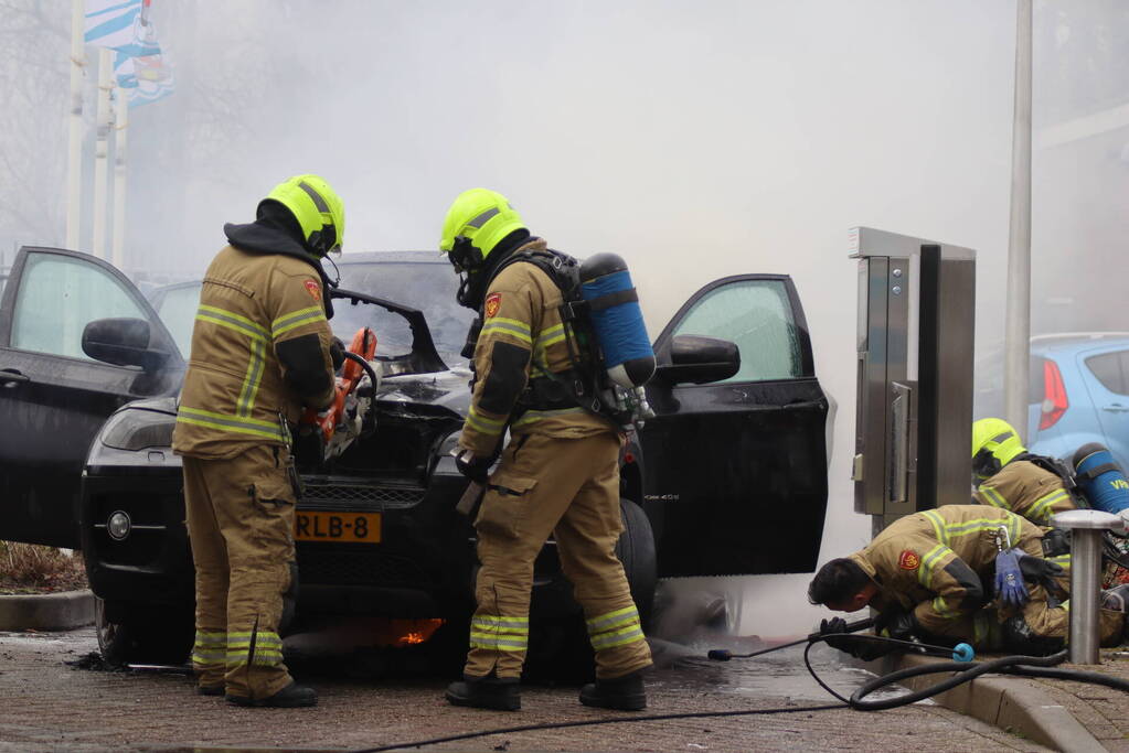 Auto vliegt in brand voor ingang carwash