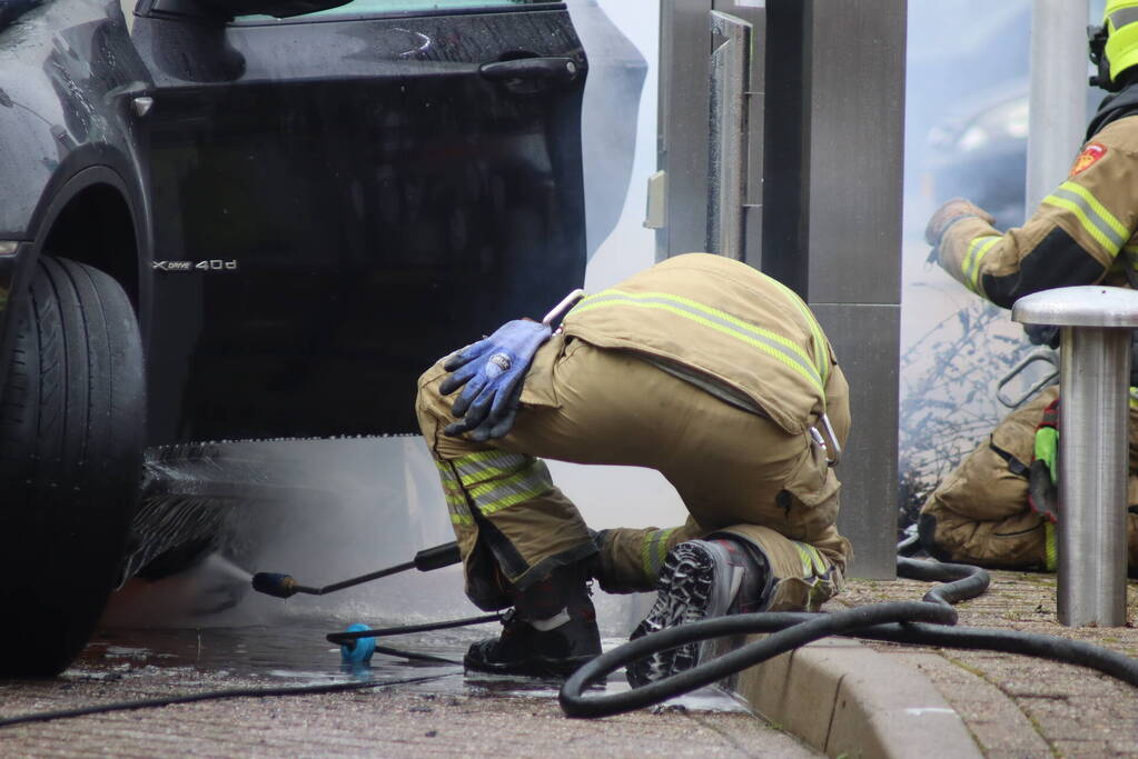 Auto vliegt in brand voor ingang carwash