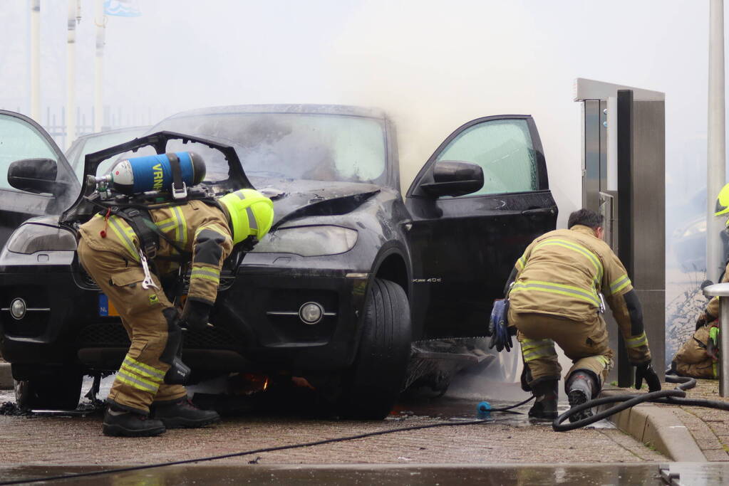 Auto vliegt in brand voor ingang carwash