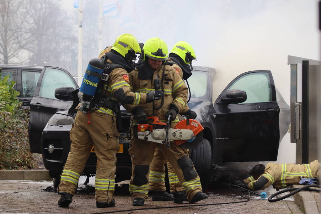 Auto vliegt in brand voor ingang carwash