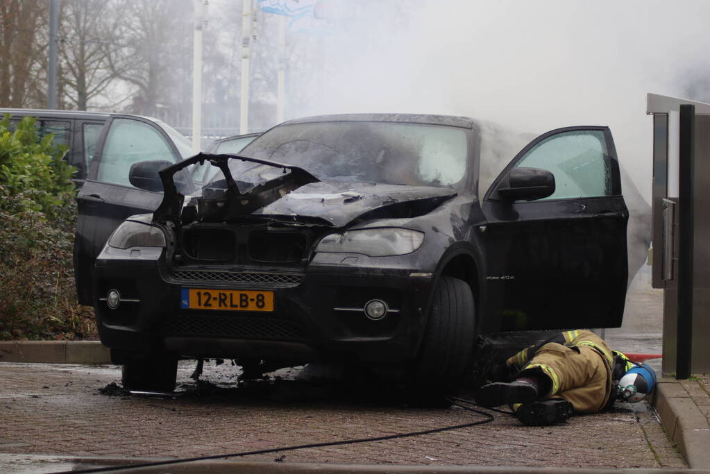 Auto vliegt in brand voor ingang carwash