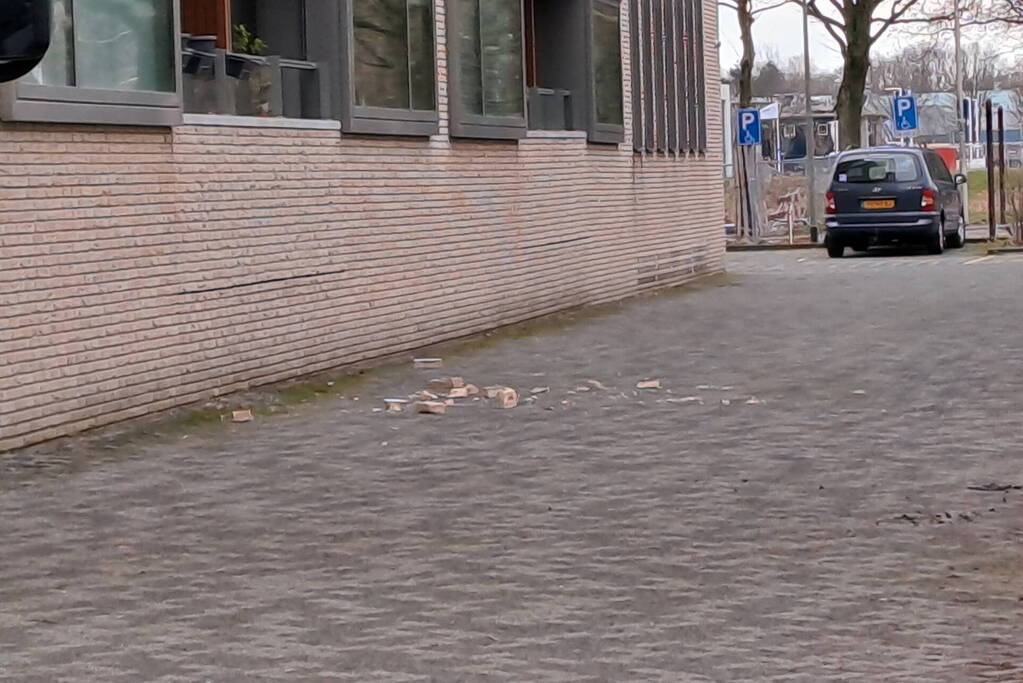 Bakstenen vallen uit gevel van flatgebouw