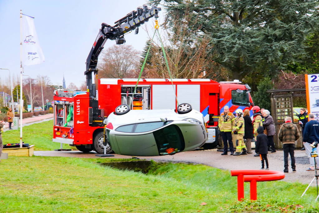 Brandweer takelt auto uit greppel