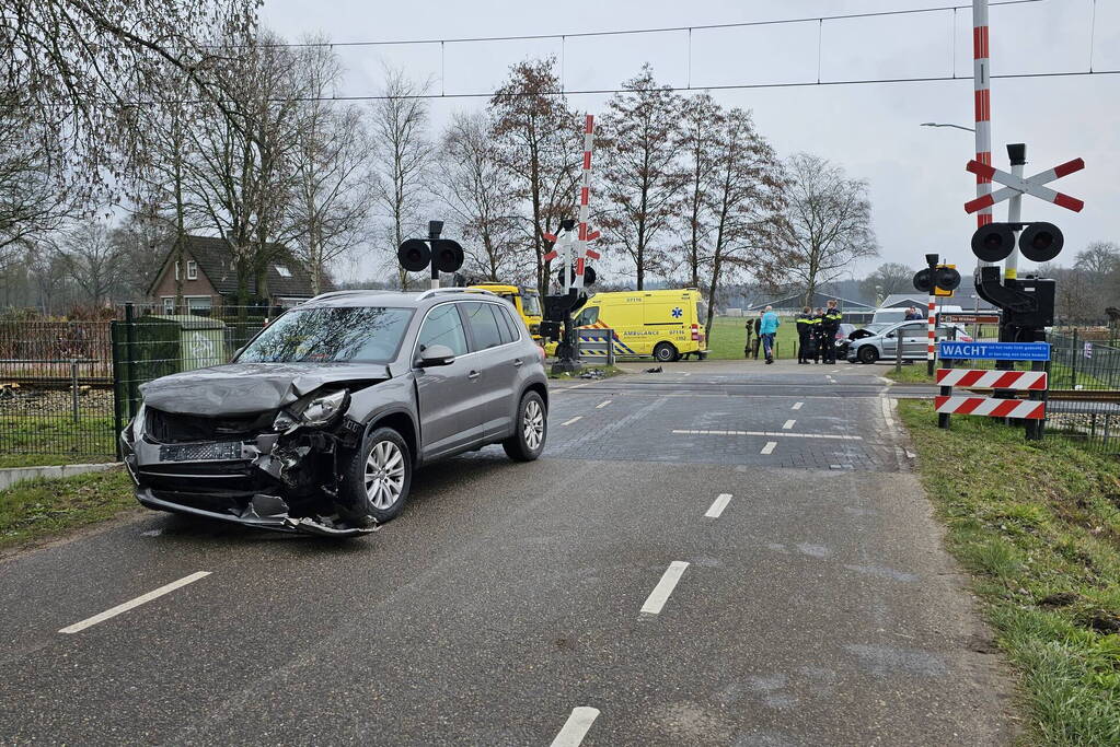 Twee auto's botsen tegen elkaar bij spoorwegovergang