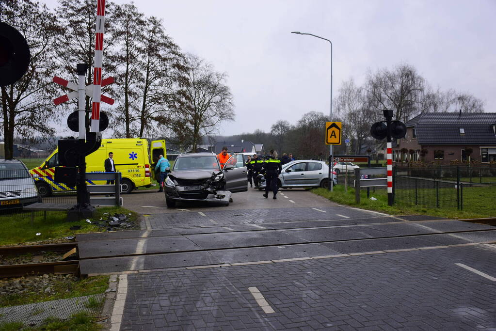 Twee auto's botsen tegen elkaar bij spoorwegovergang