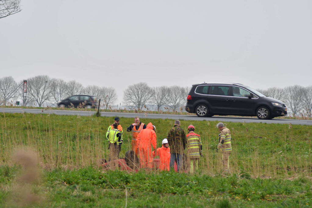 Auto belandt op zijn kop naast snelweg
