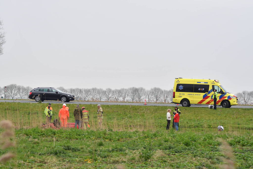 Auto belandt op zijn kop naast snelweg