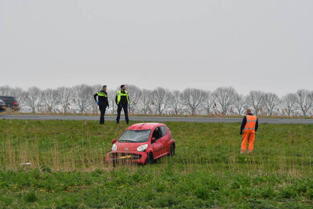 Auto belandt op zijn kop naast snelweg