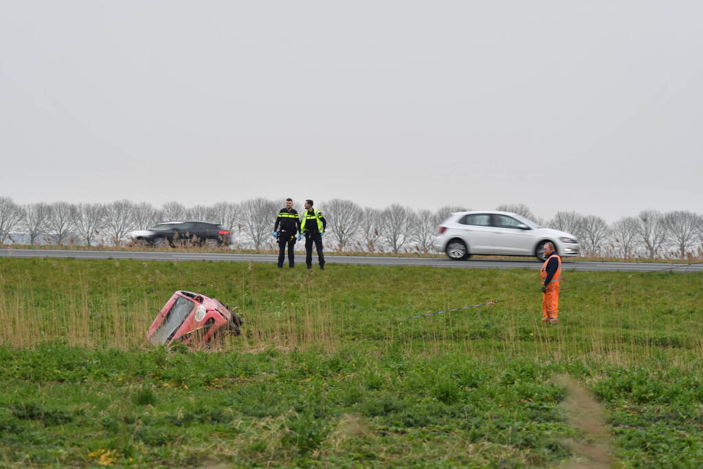 Auto belandt op zijn kop naast snelweg