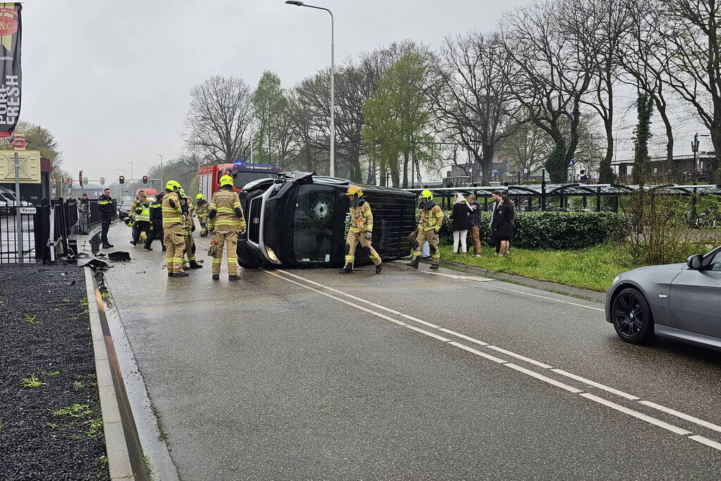 Bestelbus botst op hek en belandt op zijkant