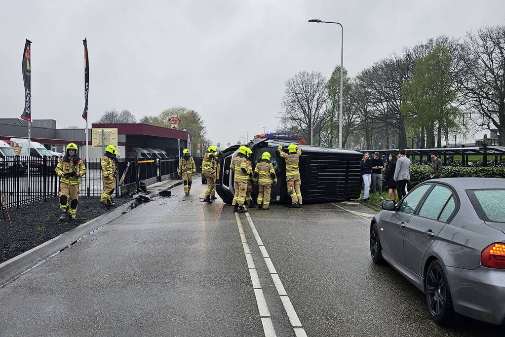 Bestelbus botst op hek en belandt op zijkant