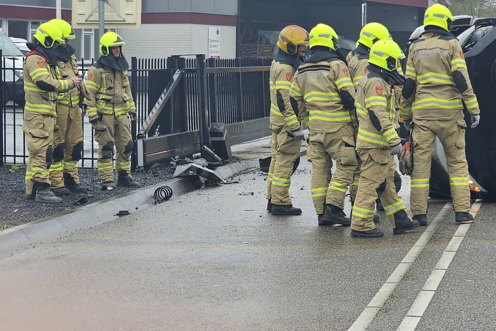 Bestelbus botst op hek en belandt op zijkant