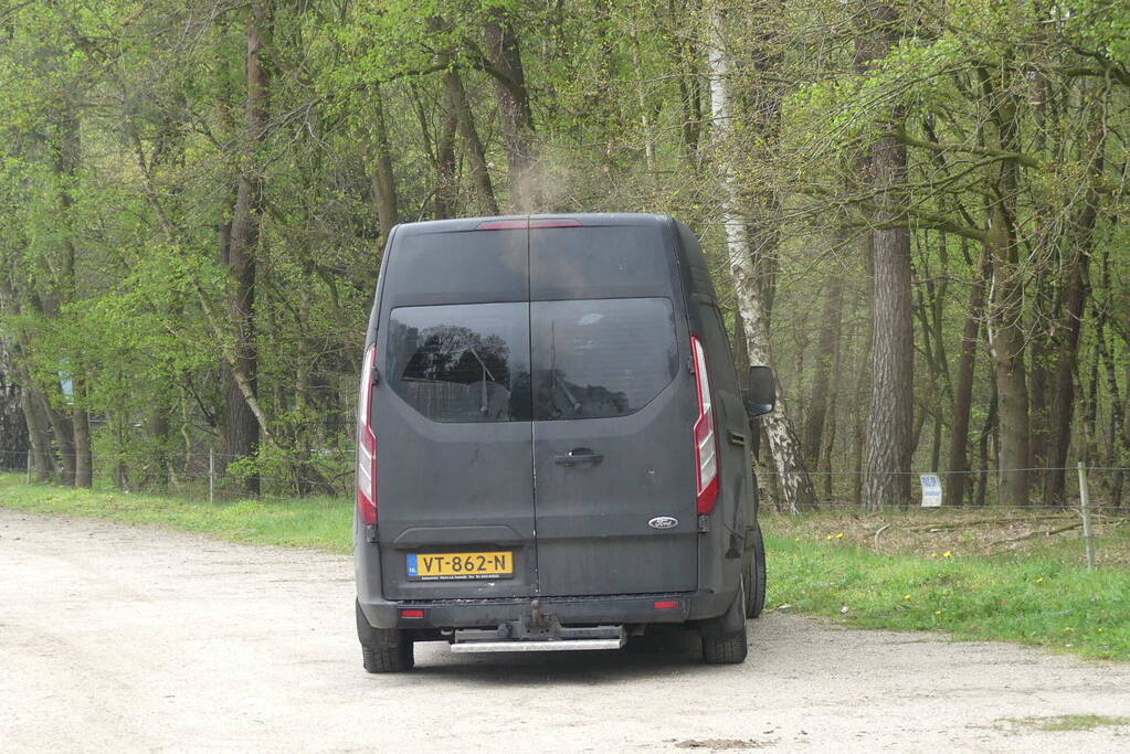 Bestelbus met afval in brand gestoken op parkeerplaats bij bos, twee aanhoudingen