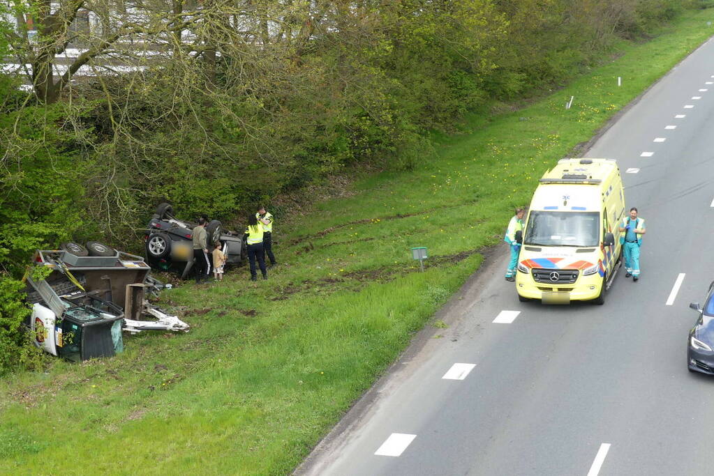 Auto en aanhanger met graafmachine over de kop