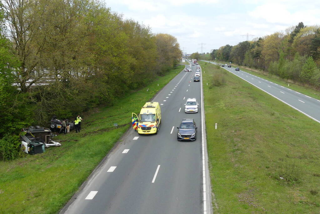 Auto en aanhanger met graafmachine over de kop