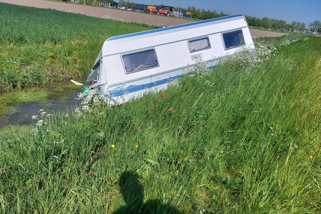 Caravan raakt los van auto en belandt in sloot