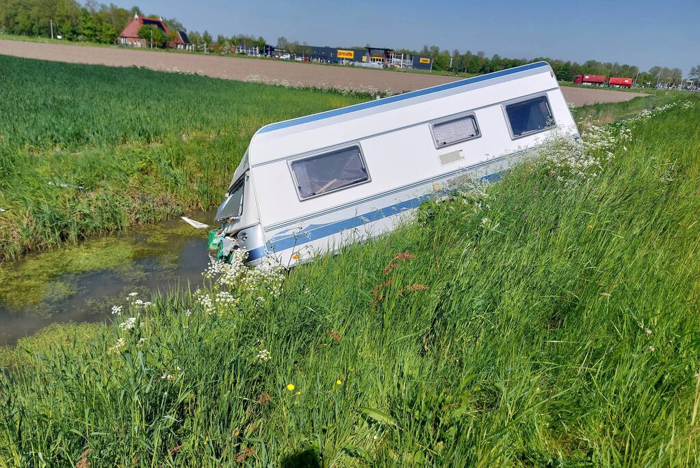 Caravan raakt los van auto en belandt in sloot