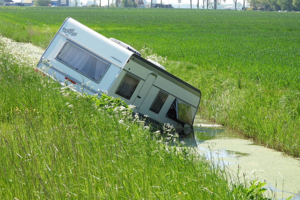 Caravan raakt los van auto en belandt in sloot