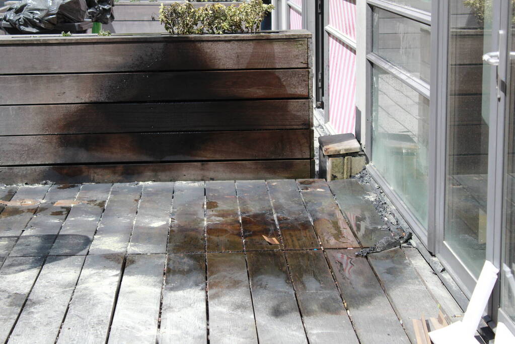 Schade aan vlonder na brand in stapel karton