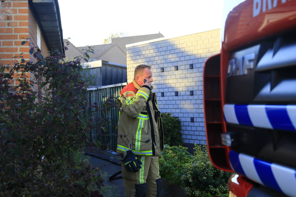 Brandweer blust brandende prullenbak in schuur