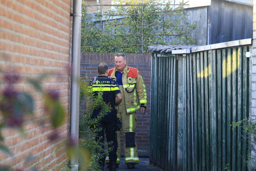Brandweer blust brandende prullenbak in schuur