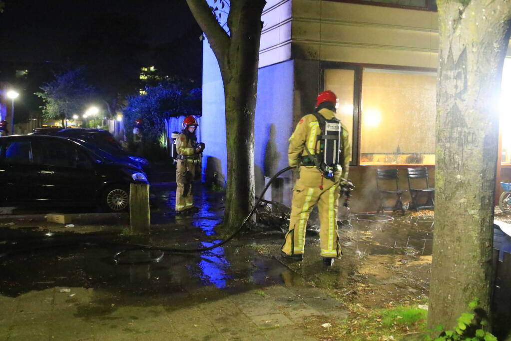 Scooter in brand tegen woning