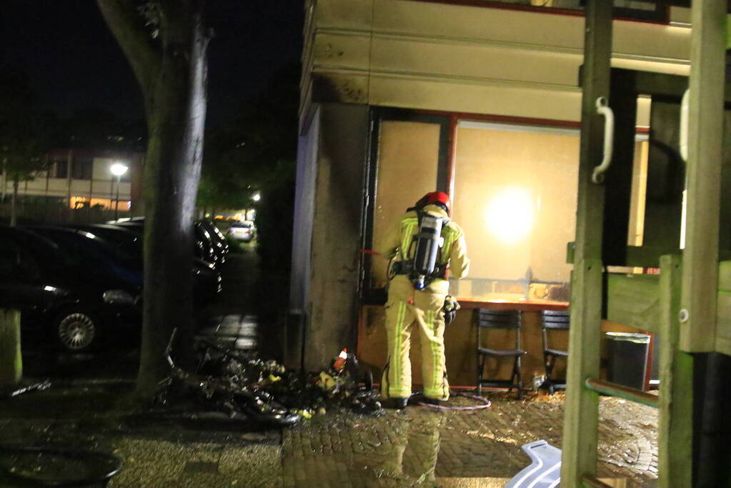 Scooter in brand tegen woning