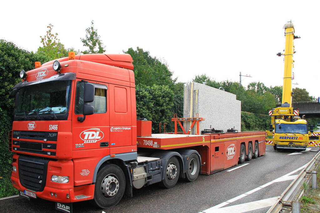 Vrachtwagen geladen met betonplaten vast onder spoorbrug