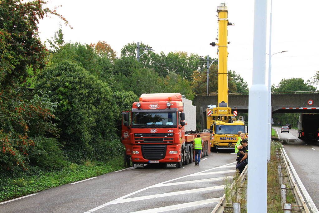 Vrachtwagen geladen met betonplaten vast onder spoorbrug