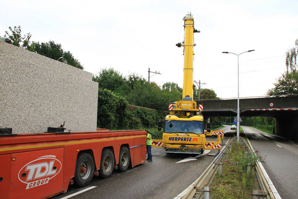 Vrachtwagen geladen met betonplaten vast onder spoorbrug