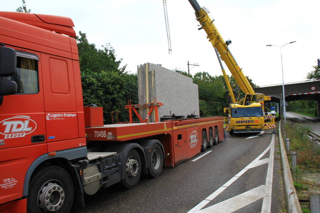 Vrachtwagen geladen met betonplaten vast onder spoorbrug