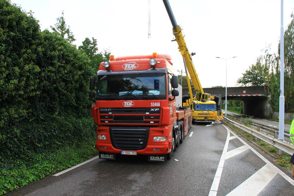 Vrachtwagen geladen met betonplaten vast onder spoorbrug
