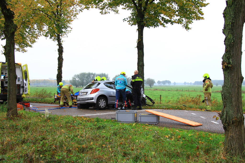 Bestuurder bekneld bij botsing tegen boom