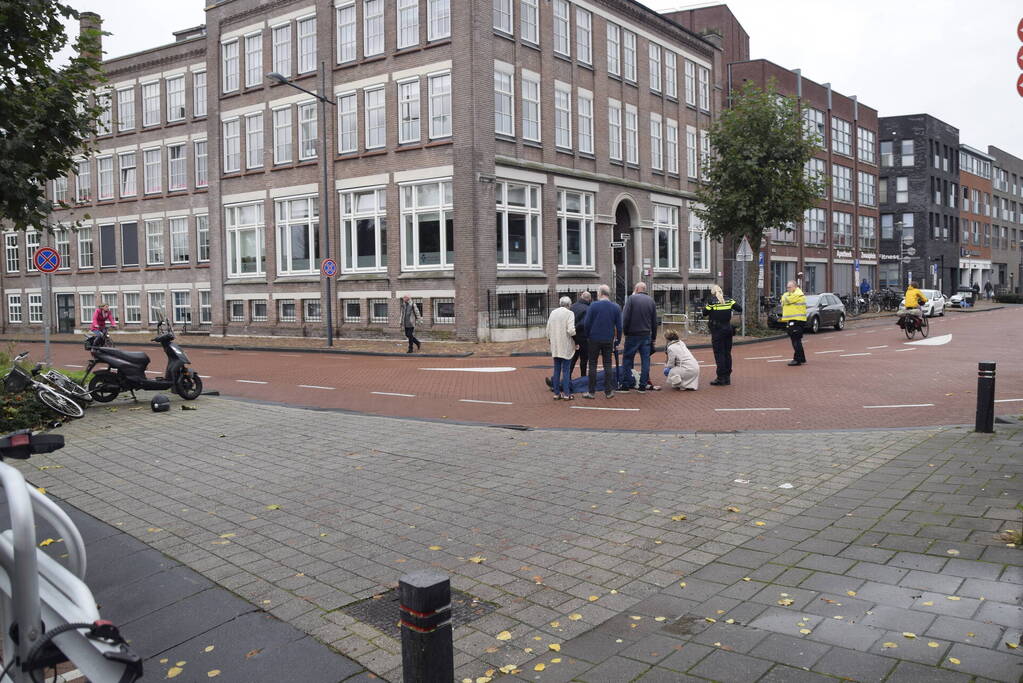 Persoon op scooter onderuit op kruising