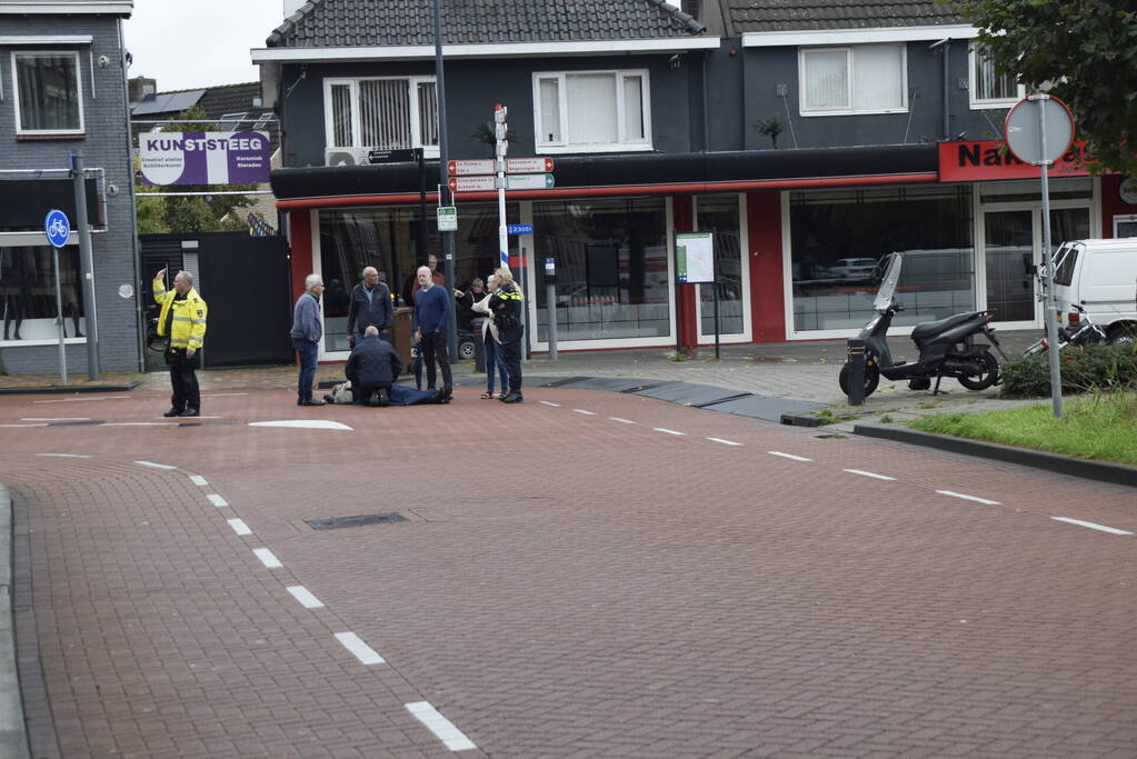 Persoon op scooter onderuit op kruising