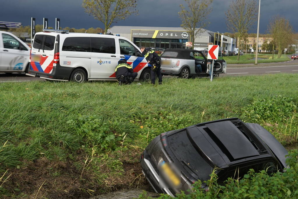 Omstanders halen inzittenden uit te water geraakt voertuig