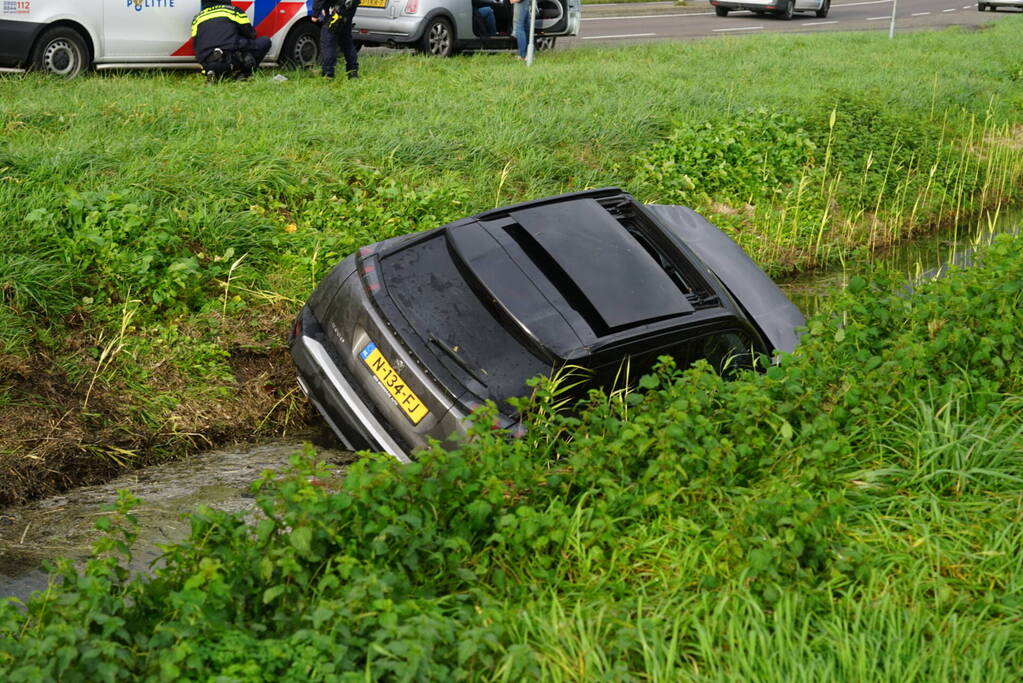 Omstanders halen inzittenden uit te water geraakt voertuig