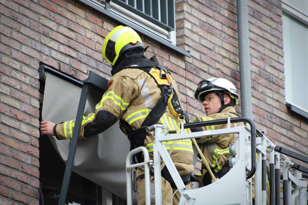 Brandweer zet loshangende zonnescherm vast