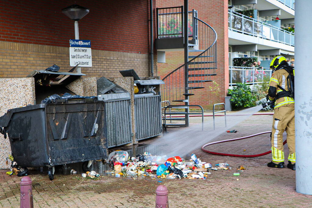 Containers onder flatgebouw in brand