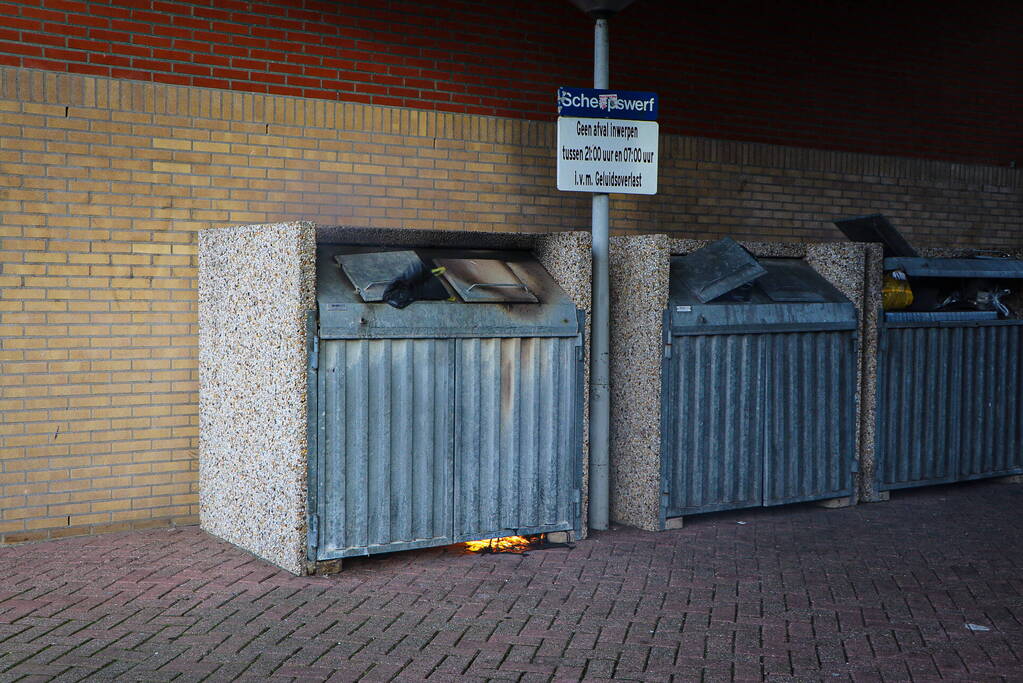 Containers onder flatgebouw in brand