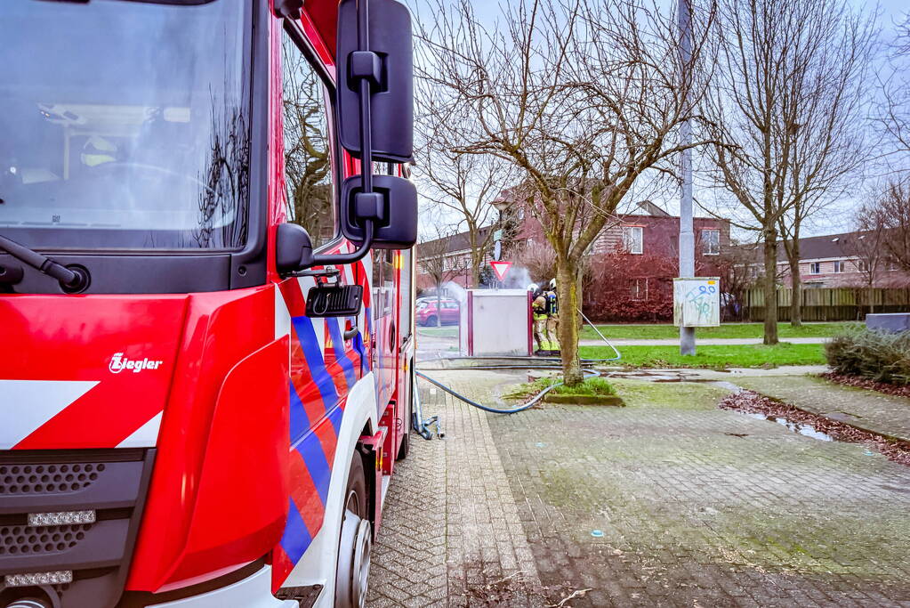 Brandweer blust brandende papiercontainer
