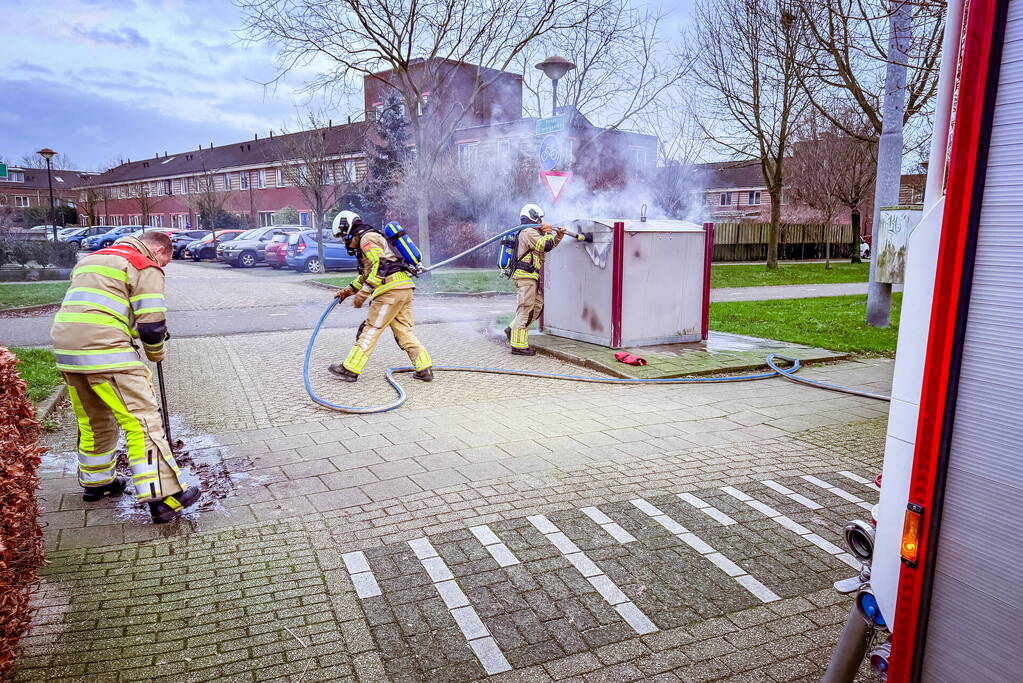 Brandweer blust brandende papiercontainer
