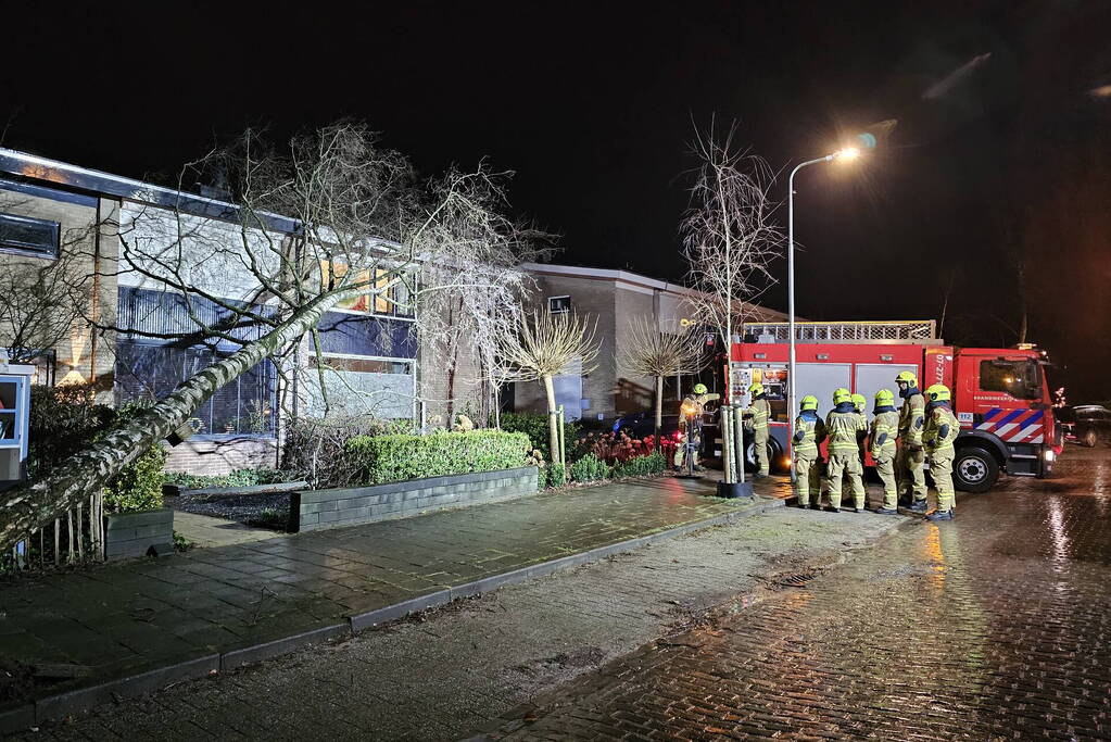 Grote boom waait om en belandt tegen woning