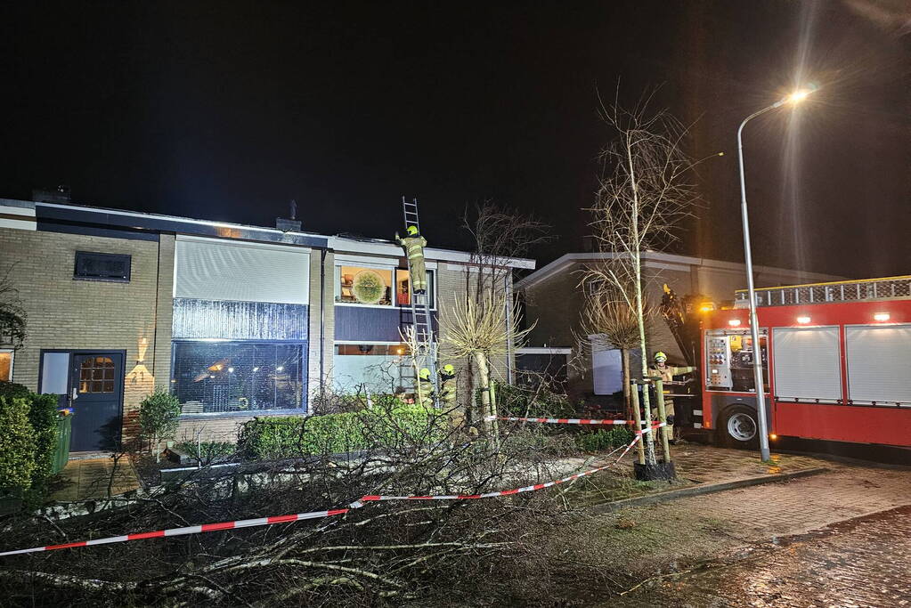 Grote boom waait om en belandt tegen woning