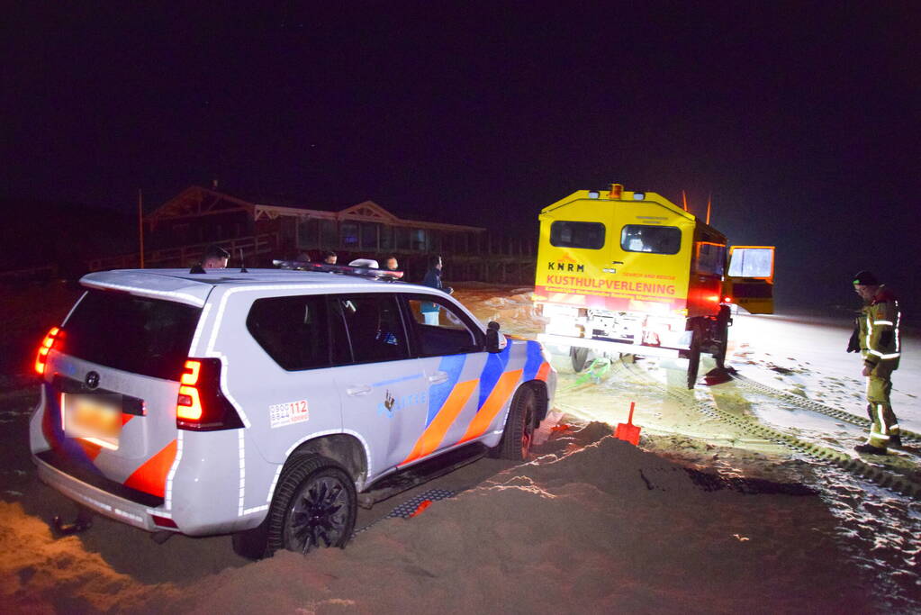 Politiejeep muurvast in los zand op strand