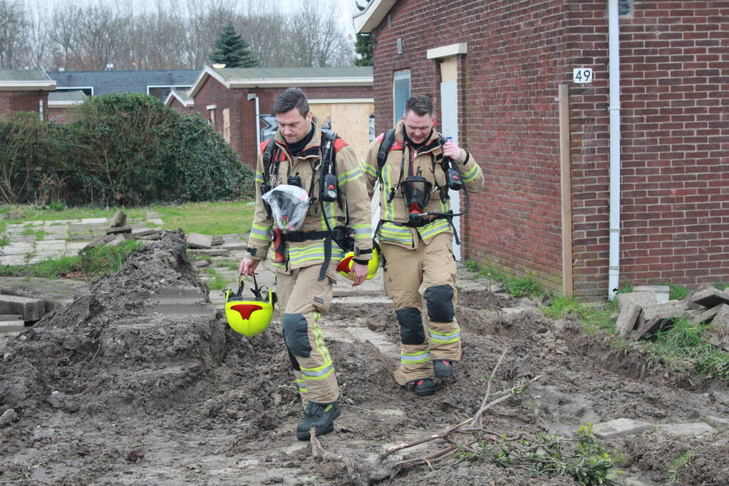 Brandweer blust brandend afval achter sloopwoningen