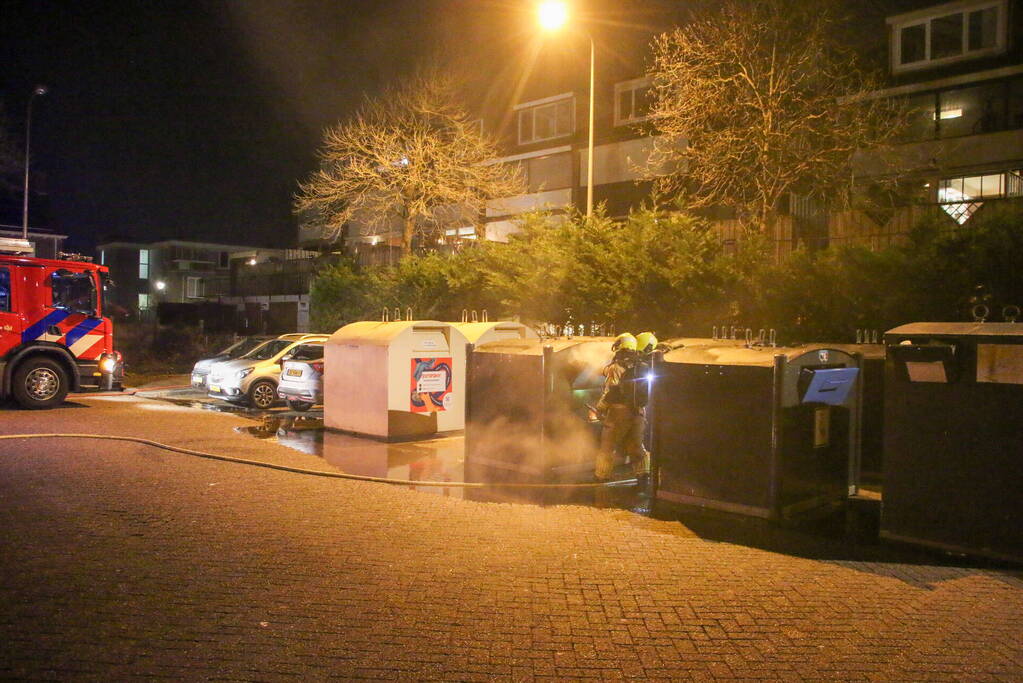 Brandweer blust brandende papiercontainer