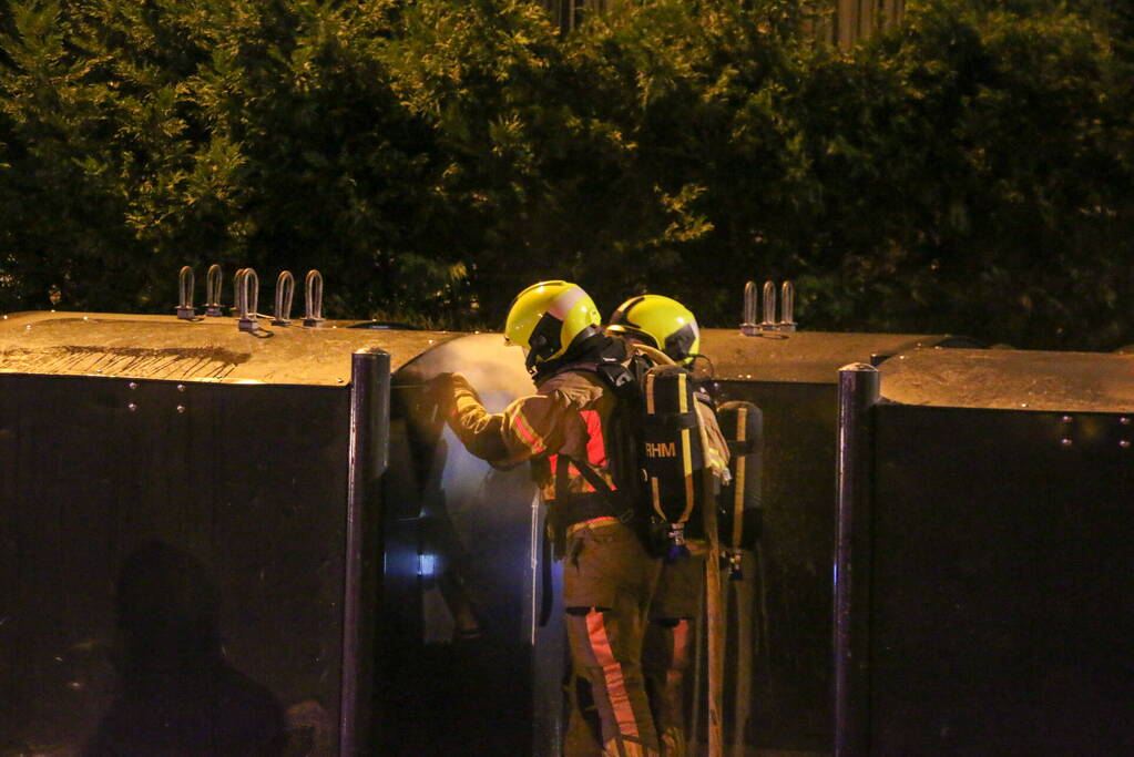 Brandweer blust brandende papiercontainer