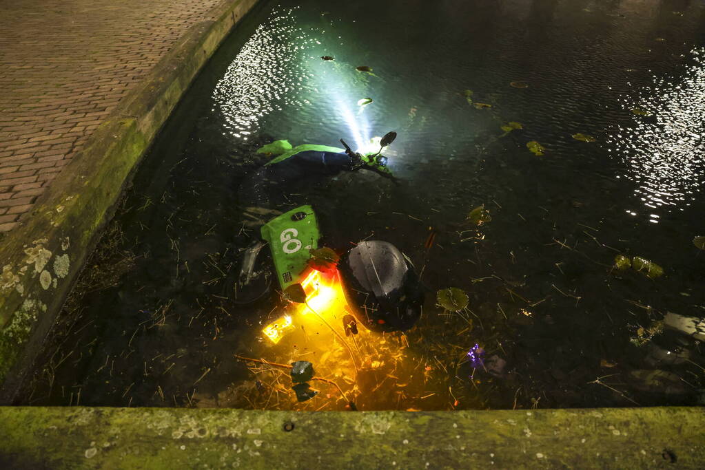 Personen dumpen scooter in vijver met karpers