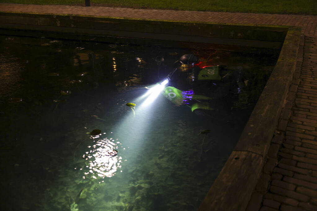 Personen dumpen scooter in vijver met karpers